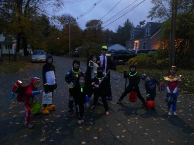 lots of kids in costumes posing on the street at dusk