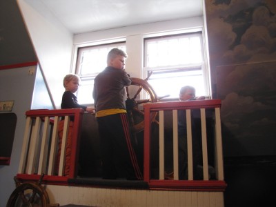 three boys playing with the ship's wheel at the Discovery Museum