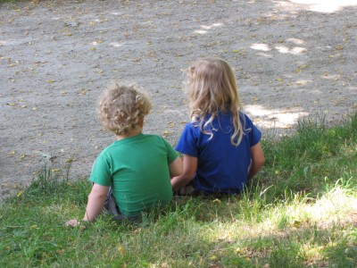 Harvey and Tristan sitting on the grass, from behind