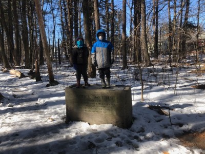Zion and Elijah standing on the ice in the horse trough in our woods