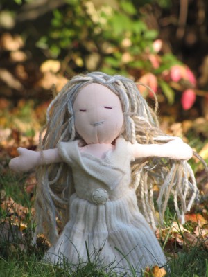 a doll with a white dress and pale hair photographed on the lawn