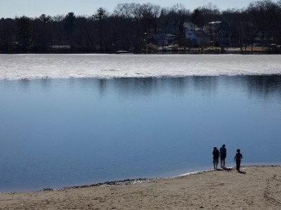 kids standing on the beach at Freeman Pond with ice off in the distance