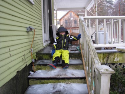 Zion in his new snowsuit sliding down the porch steps on his butt