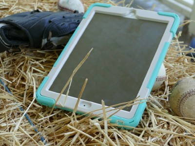an iPad, baseballs, and a mitt on a haybale