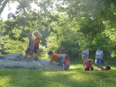 the boys and other kids playing around a big rock