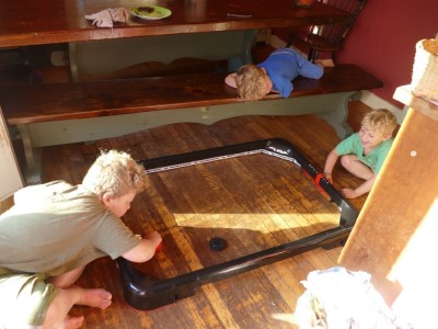 Harvey and Zion playing air-hockey on the kitchen floor