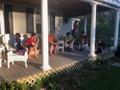 lots of kids sitting on a porch in evening light