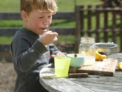 Lijah puckering as he tastes the lemondade he's making, out on the porch