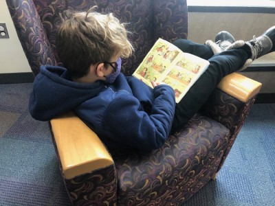 Elijah sprawled in a chair at the library reading a book