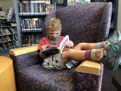 Elijah with his feet up reading in a library chair