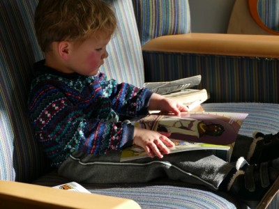 Lijah on a couch at the library, looking at a book