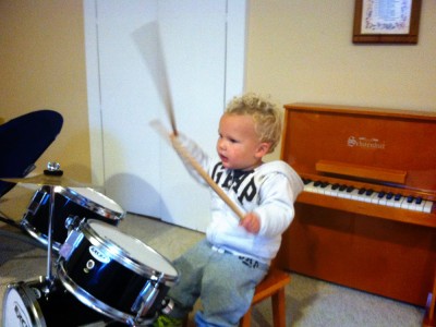 Lijah wailing on the mini drum kit in front of the mini piano