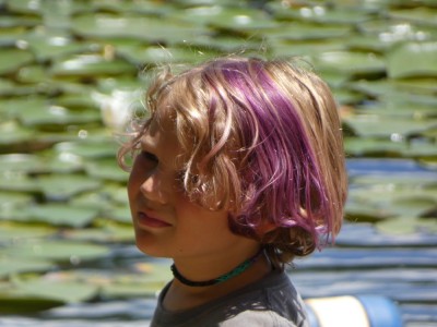 Elijah with purple-streaked hair and a choker by some lily pads