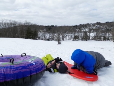 Zion and Harvey lying down at the top of the sledding hill