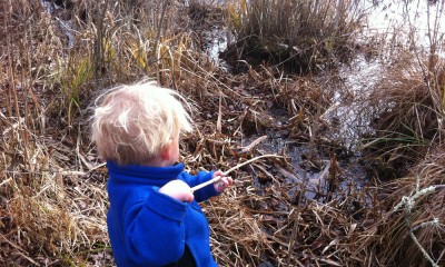 Zion using a big reed stem to pretend to fish in the stream