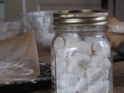 a ball jar of mini marshmallows foreground, messy table background