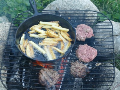 hamburgers and french fries cooking on the fire