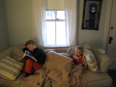 the boys on the couch: harvey reading, zion under a blanket, lijah with a sword