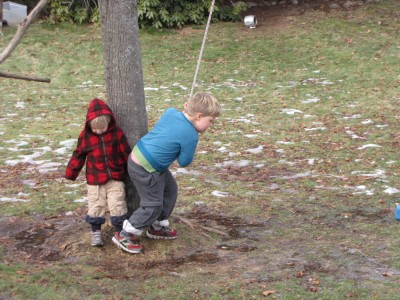 Harvey ready to swing on a rope across a puddle on the muddy lawn, Zion watching