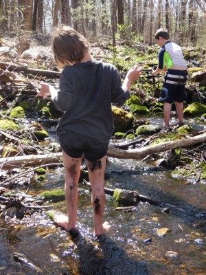 Elijah playing in a stream, lots of mud on his legs