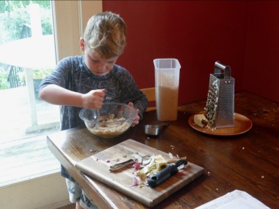 Elijah stirring apple muffin batter at the kitchen table