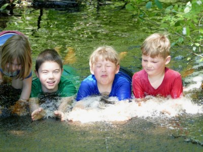 Zion, Elijah, and friends lying in a spillway lifting their faces out of the water