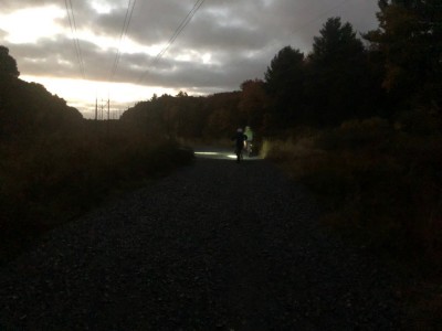 Harvey and Zion riding a gravel road at dawn, with headlamps