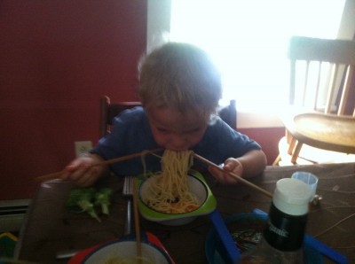 Zion eating spaghetti with chopsticks--one in each hand