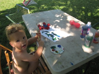 naked Lijah woeking on painting on a table outside