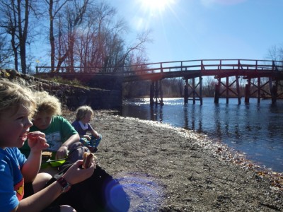 the boys eating lunch on the gravelly beach by the Old North Bridge
