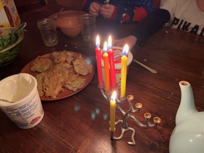 our menorah with red and yellow candles on the table with latkes and sour cream