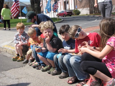 eight or so kids sitting on the curb waiting for the parade