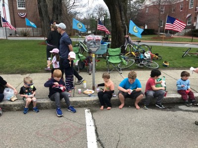 the kids sitting on the curb eating treats waiting for the parade