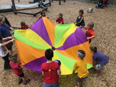 the boys playing with a parachute with lots of other kids