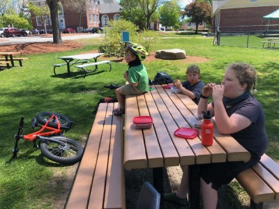 the boys eating lunch at a picnic table at the playground
