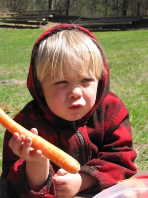 Zion at a picnic table holding a carrot