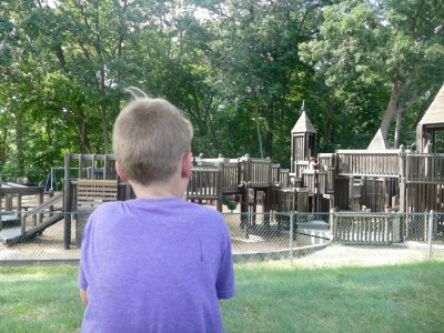 Elijah looking at a towery wooden playground