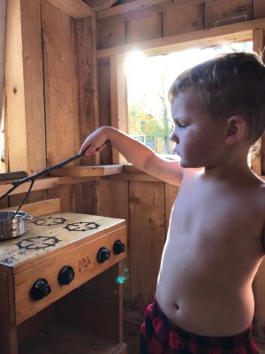 Lijah concentrating on cooking in the playhouse