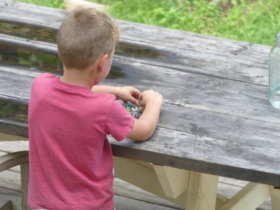 Elijah playing with little plastic pokemon at the picnic table