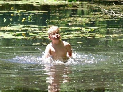 Zion splashing more than waist deep in the pond