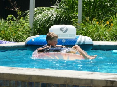Elijah floating in a pool on a donut thing