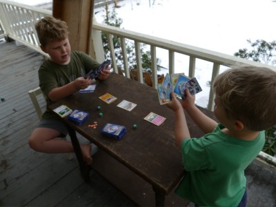 Harvey and Zion playing pokemon cards on the porch