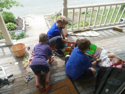 Zion, Elijah, and a friend playing with toys on the front porch