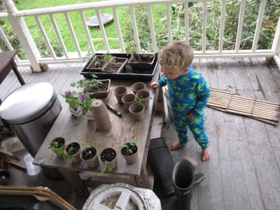 Lijah in PJs looking at my tomato seedlings in pots