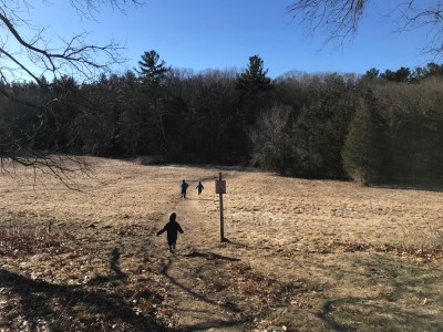 the boys running across a field on a hike