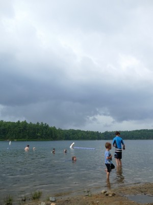 the kids in the water at Walden Pond under ominous gray clouds