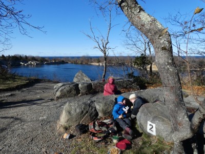 the boys huddling behind a rock to eat lunch above a quary pond