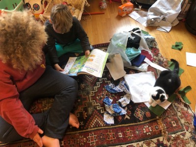 Harvey and Elijah sitting on the floor with a cat among quilting scraps