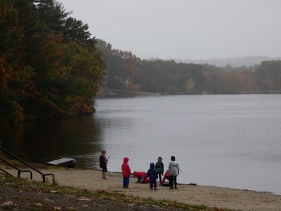 kids playing on a pond beach in windy drizzle