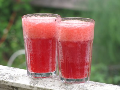 two glasses of home-made raspberry soda on the porch railing